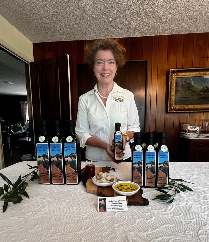 Producer displaying bottles of Bella Vista Olive Oil from Upper Suisun Valley orchard.